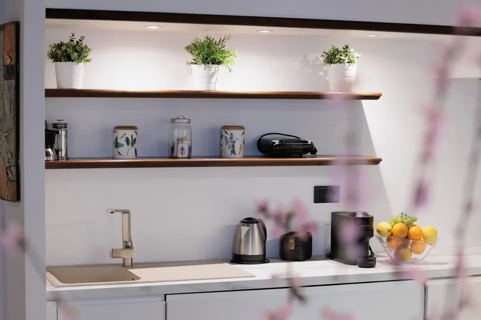 Kitchen worktop detail with kettle, a bowl of citrus and blossom in the foreground.