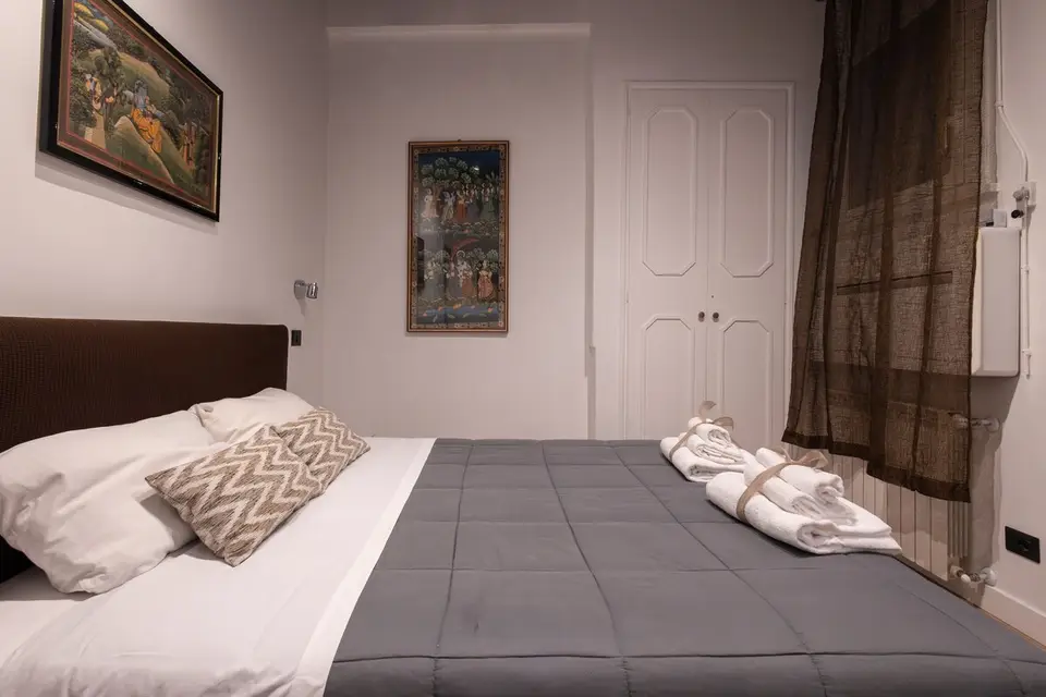 The double bed made up, folded towels laid out and prints on the walls.